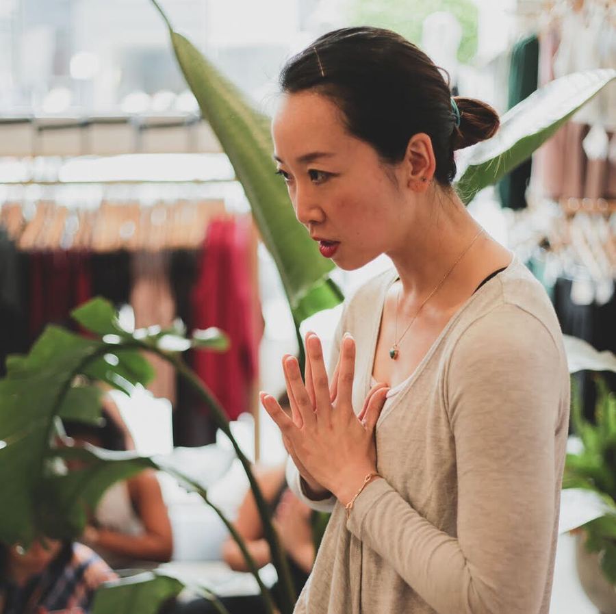 Cass with hands in prayer position among green plants
